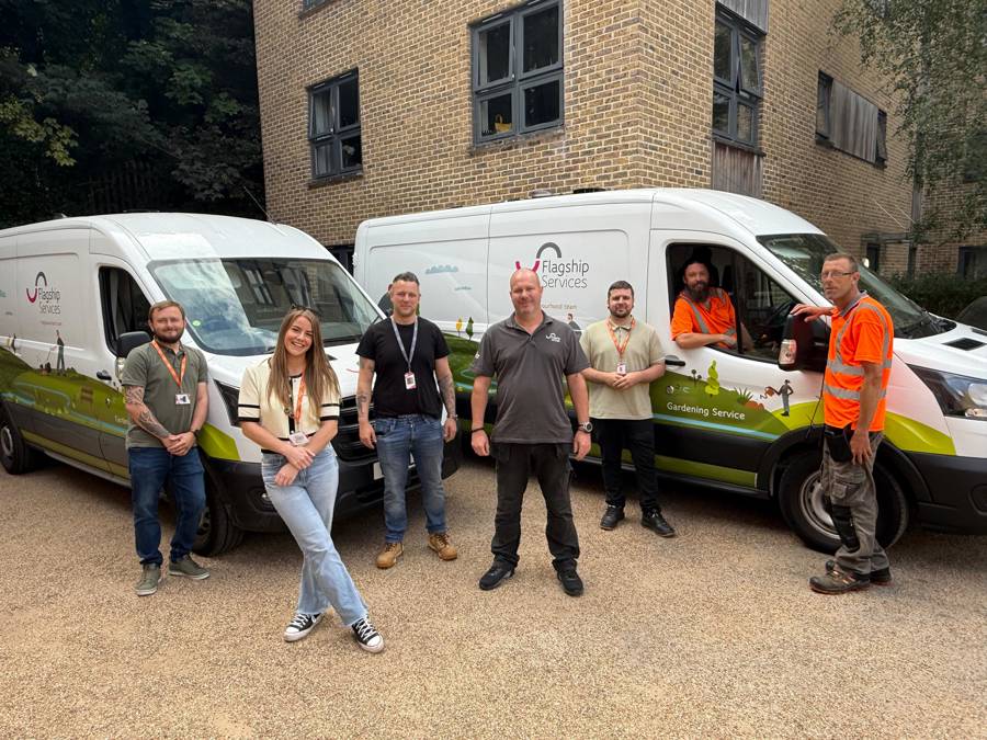 Small British landscaping team with their branded work vans on a residential street